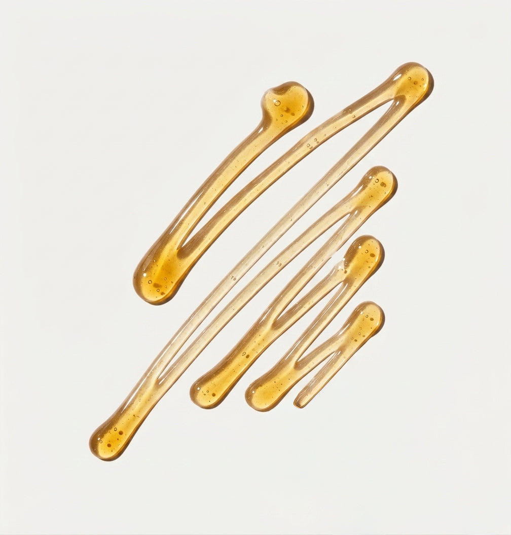 spread of amber coloured face cleanser gel in air zag pattern on a light grey background