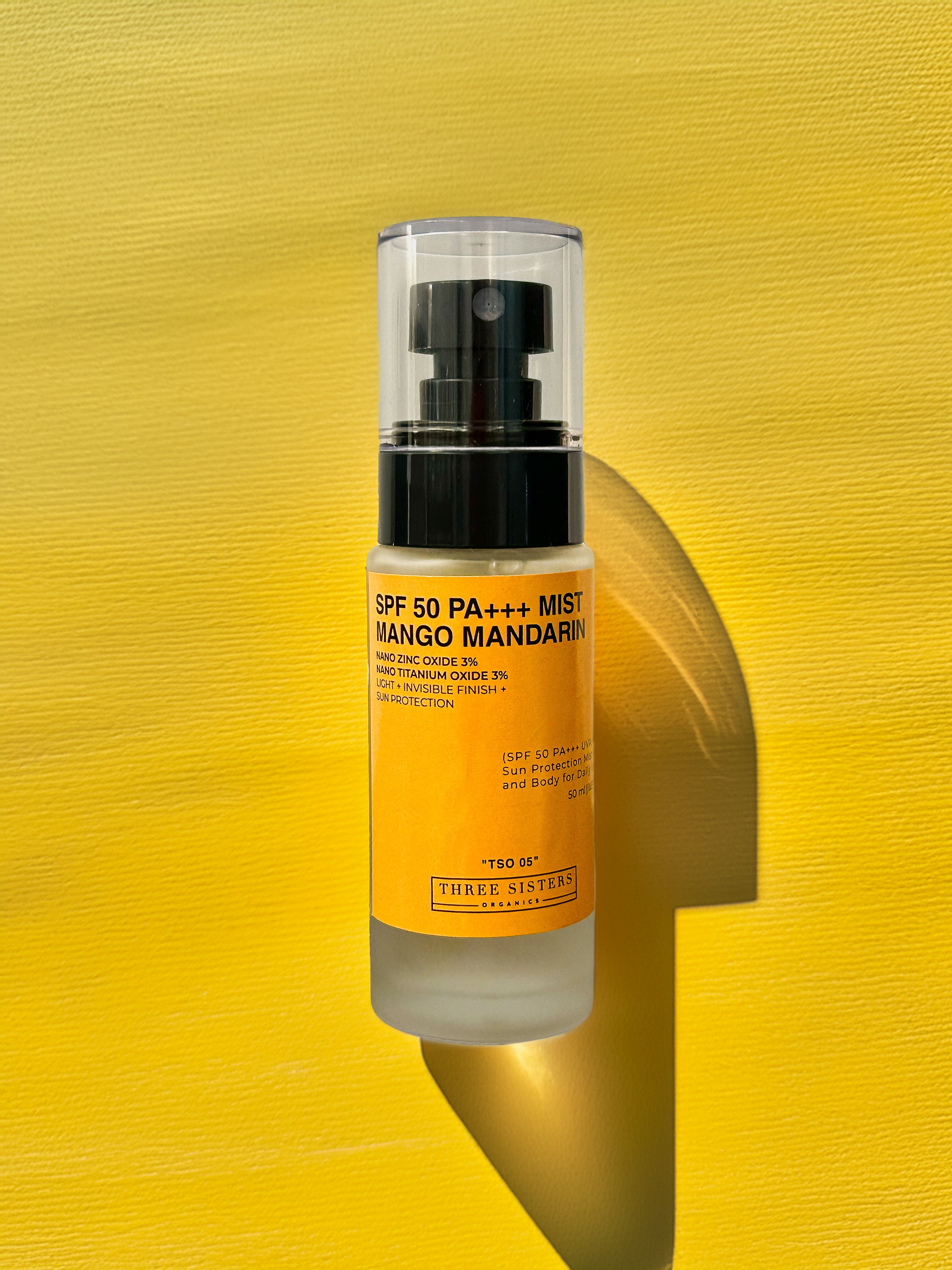 Glass bottle of spf mist mango mandarin, yellow textured background