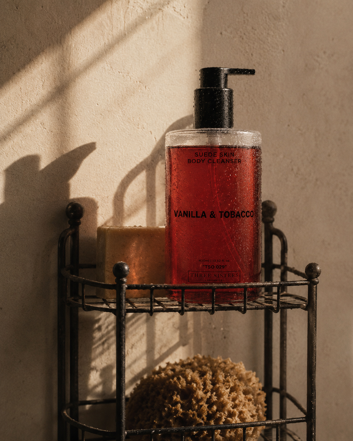 Red bottle labeled 'Vanilla & Tobacco' on a metal shelf with a beige shower wall