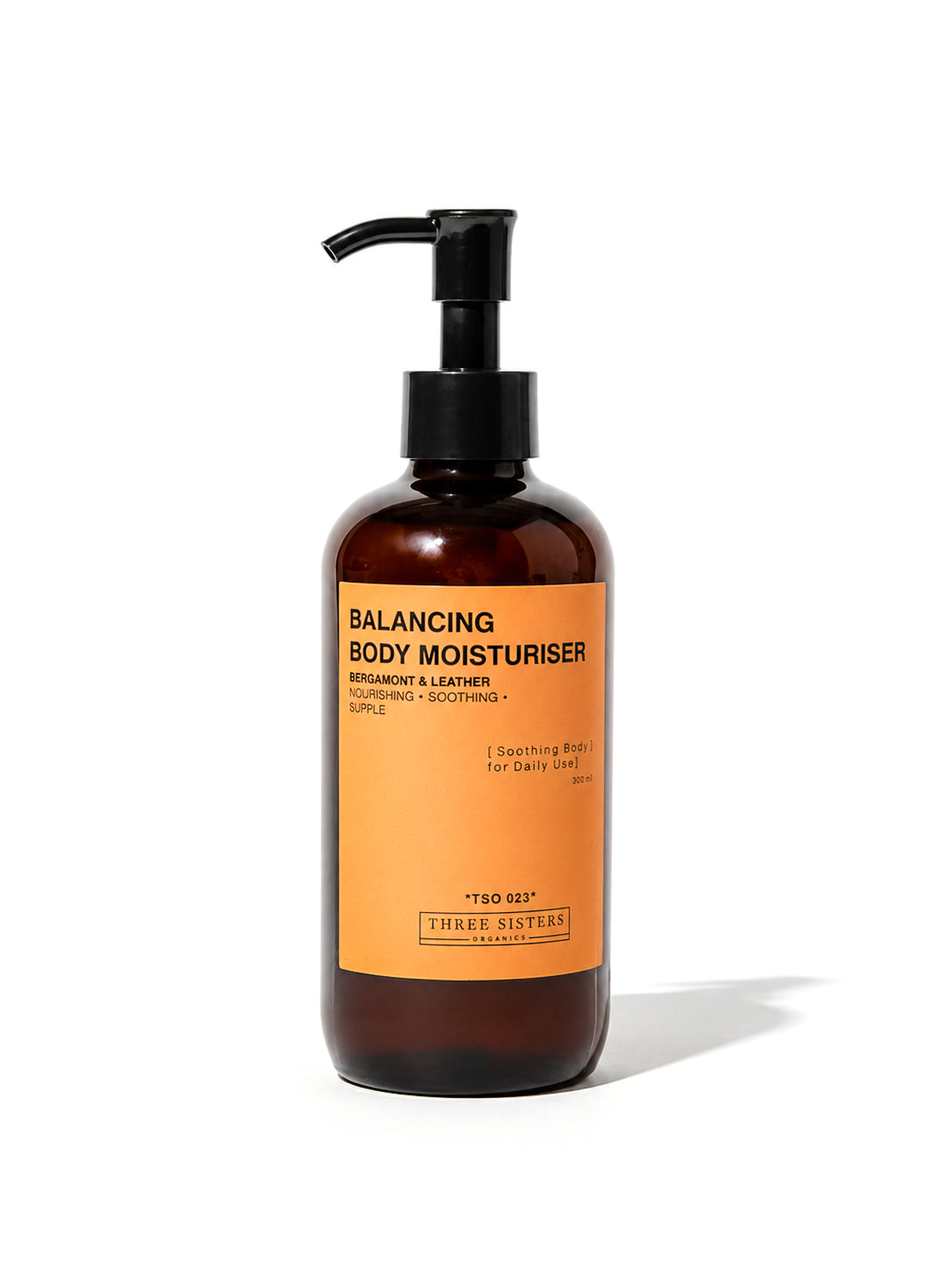 A bottle of Three Sisters Organics Balancing Body Moisturiser with a black pump dispenser and a bright orange label, set against a plain white background with a soft shadow.