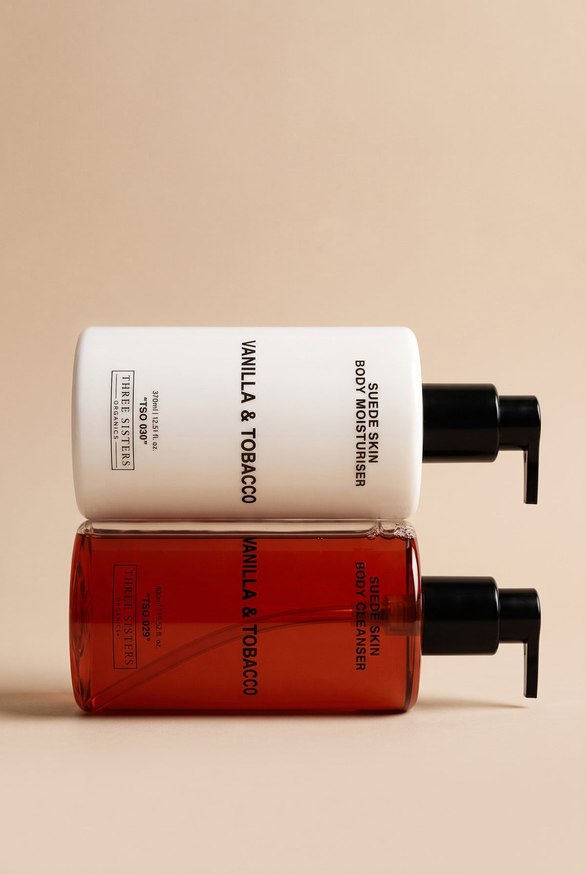 Two bottles of Vanilla & Tobacco Body Wash and Cream stacked together on a soft beige background